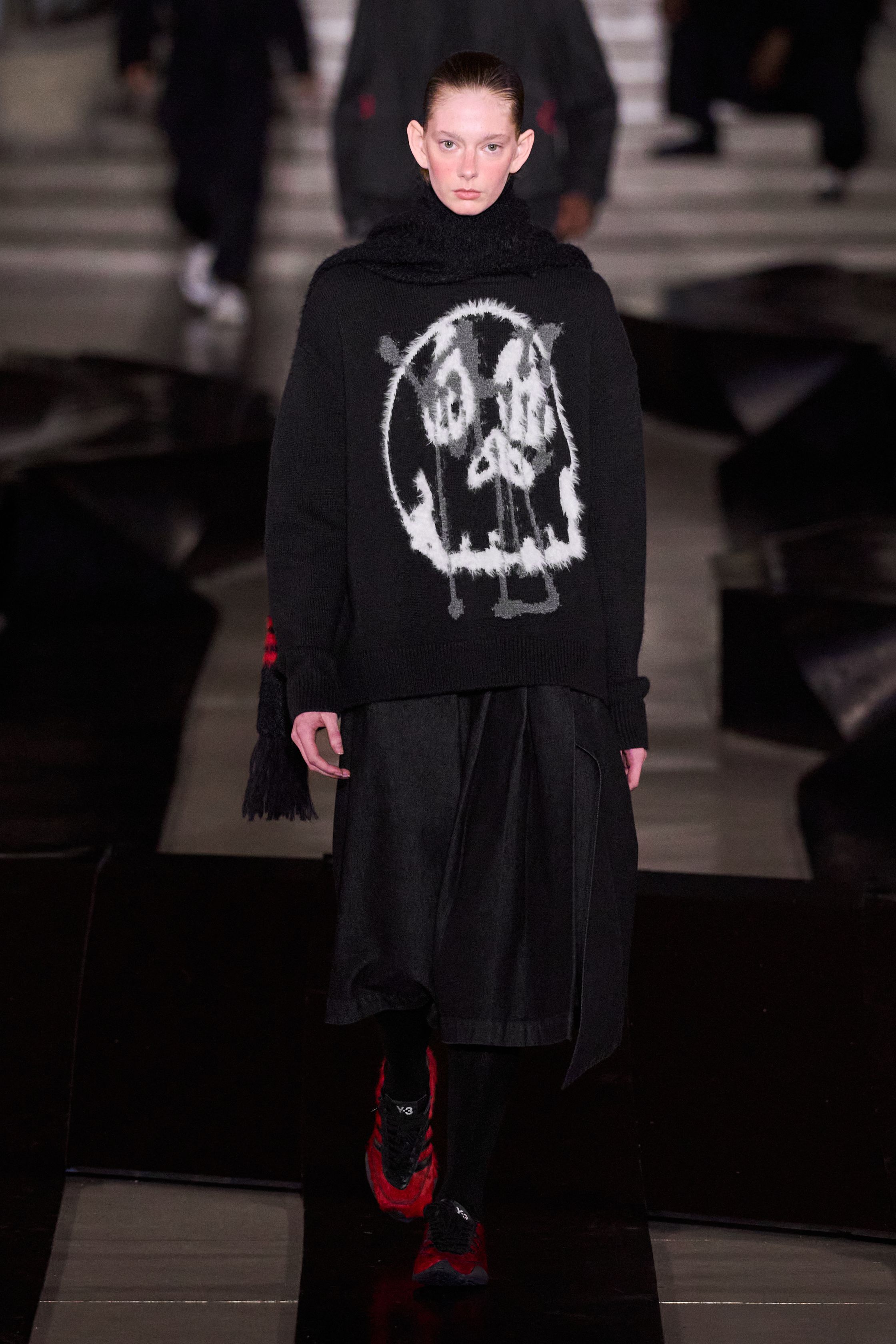 Y-3 2026 秋冬回到品牌最具力量感的“机能—反叛”核心。红黑主调贯穿全场，军装式羽绒、飞行员夹克与运动裤在宽阔比例中形成高度压迫的队列感。模特如同匿名个体行走于冷峻场景中，服装成为对秩序、权威与都市焦虑的视觉回应。本季弱化潮流化装饰，强化制服感与防护属性，体现 Yohji Yamamoto 的哲学克制与 adidas 的功能理性在极端现实语境下的再次融合-顽石频道趋势研究